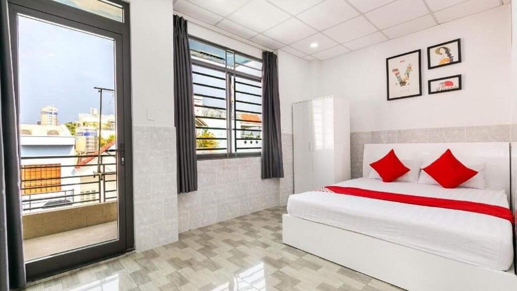 a bedroom with a bed with red pillows and a window at Vĩnh Phú Gia Hotel in Ho Chi Minh City