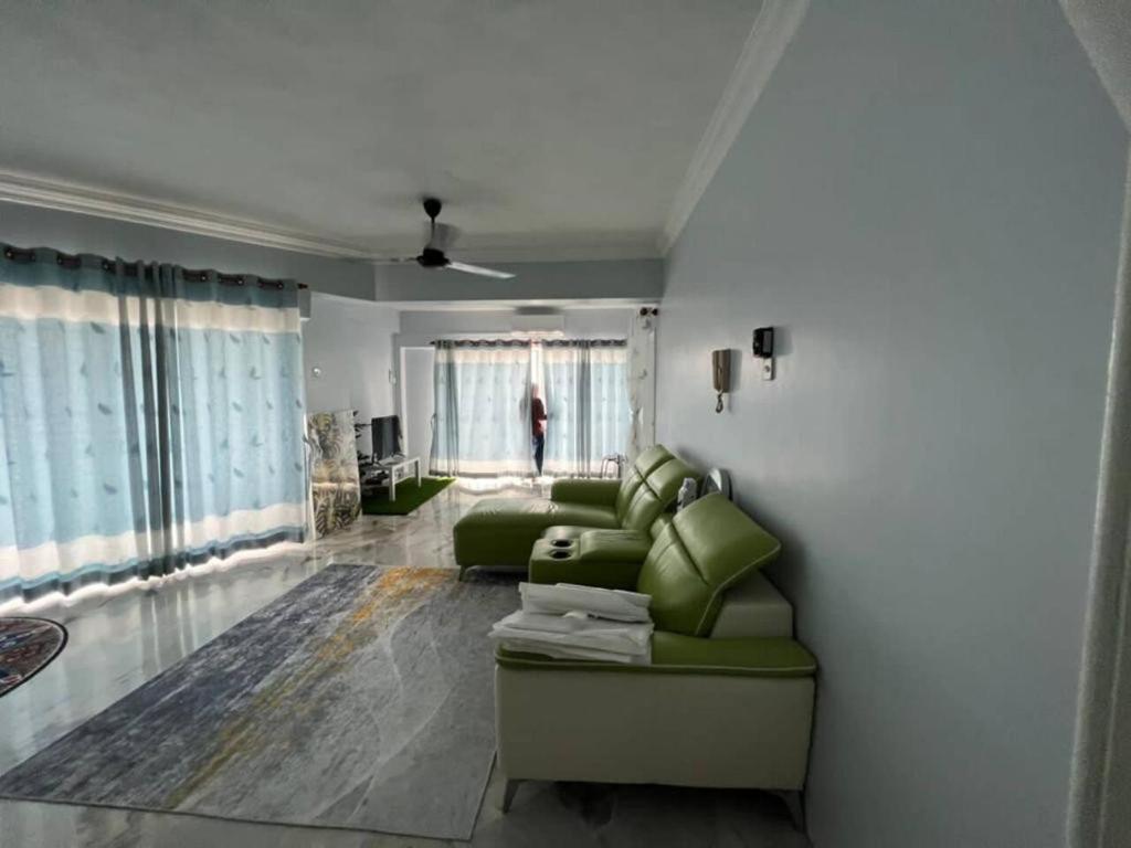 - un salon avec un canapé vert et une fenêtre dans l'établissement SADEEYA HOMESTAY (PENTHOUSE), à Kuala Lumpur