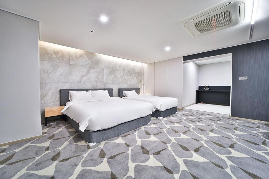 1 dormitorio con 2 camas y pared en Hotel Haydn en Busan