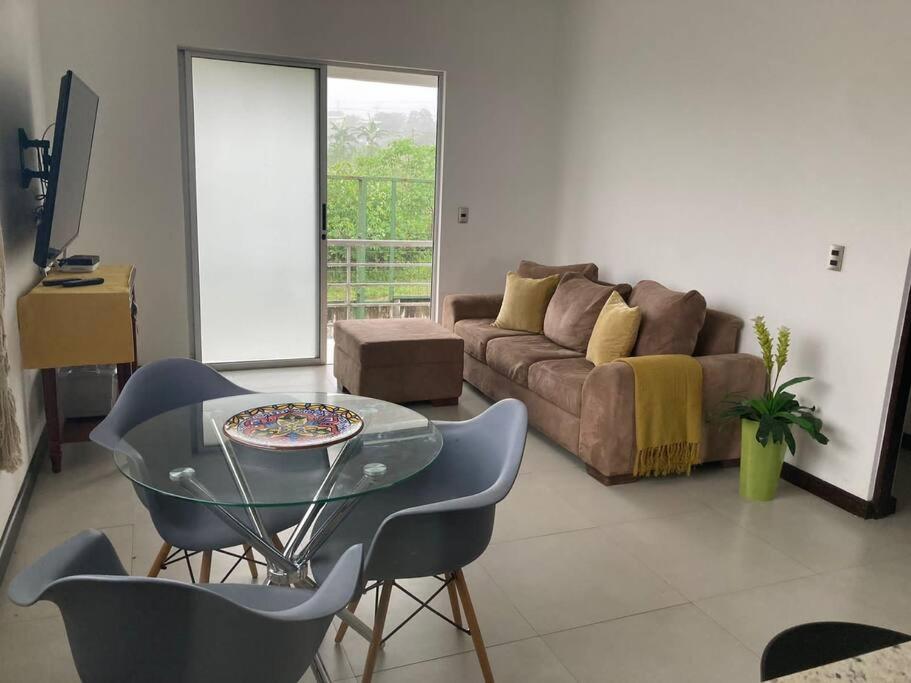 ein Wohnzimmer mit einem Sofa und einem Glastisch in der Unterkunft Hermoso Apartamento en Alajuela in Alajuela