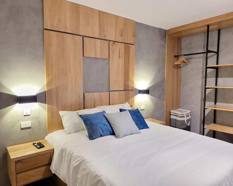 a bedroom with a large white bed with blue pillows at Center City Flats - Apartments in El Poblado near Park Lleras, Medellin! in Medellín