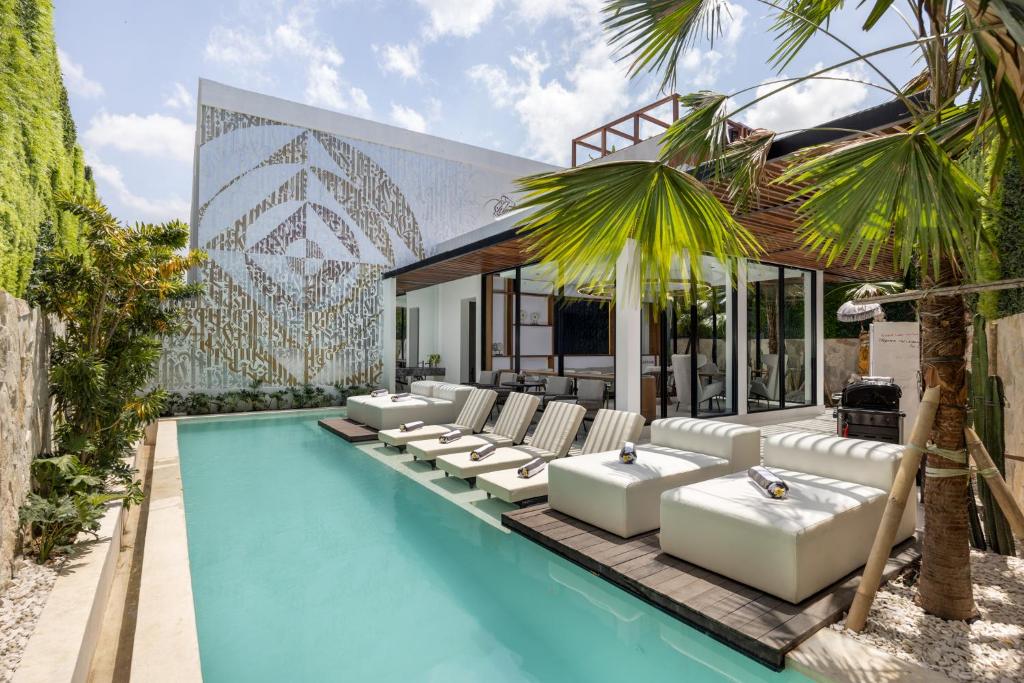 Una piscina con sillas blancas y un edificio con un mural. en Alex Villas Complex N2, en Canggu