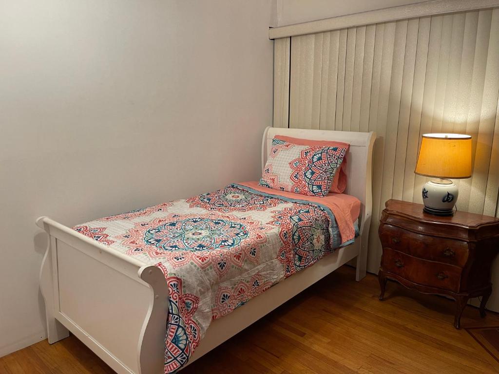 a small bedroom with a bed and a table with a lamp at Rooms in Monterey Park CA in Monterey Park