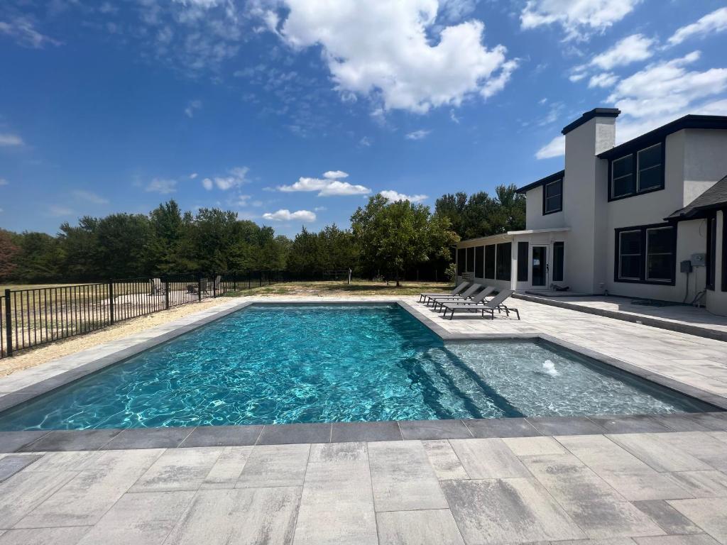 uma piscina com água azul em frente a uma casa em Luxury Ranch Retreat With Swimming Pool em Anna