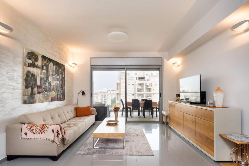 - un salon avec un canapé et une télévision dans l'établissement Beautiful Apts w/ Large Balcony & Parking by Sea N' Rent, à Tel Aviv