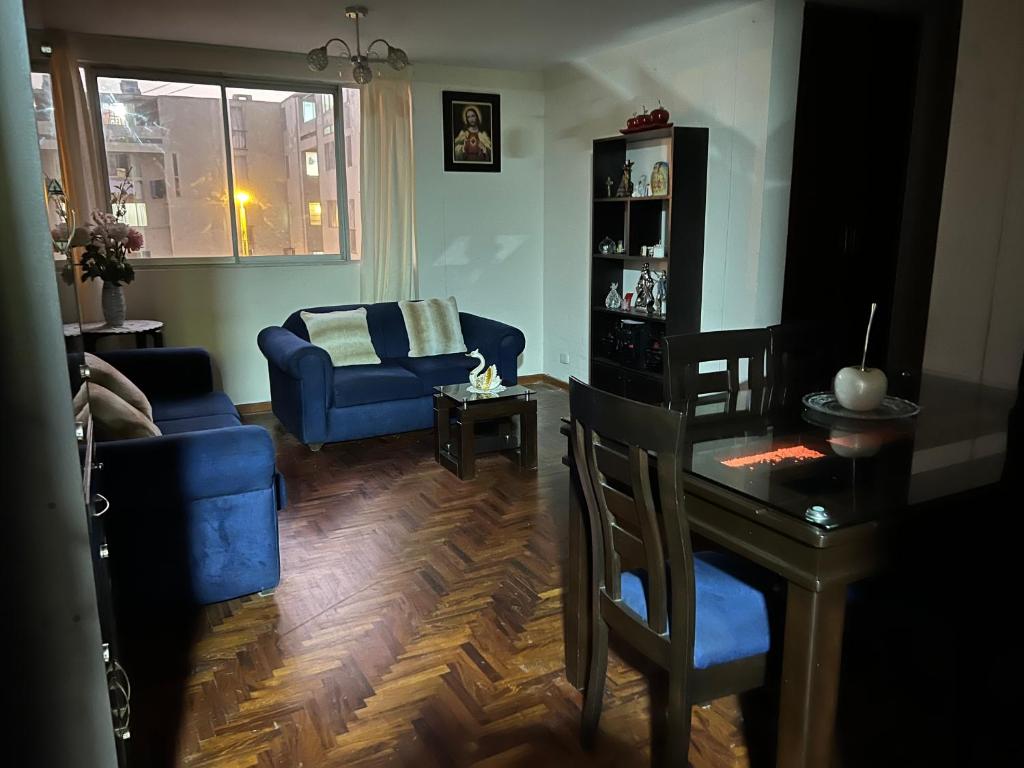 een woonkamer met een blauwe bank en een tafel bij Depa en san Miguel in Lima