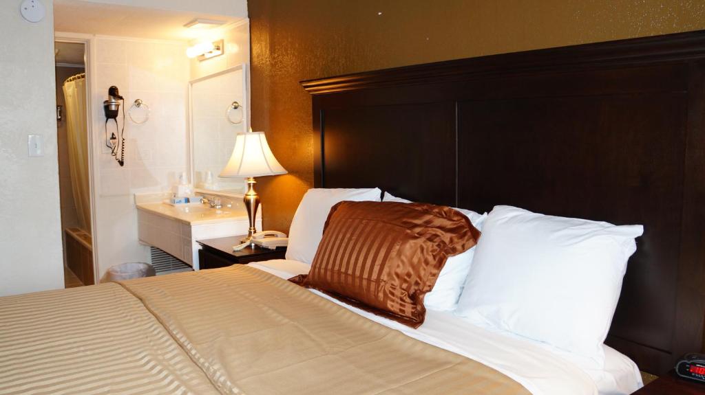 a bedroom with a large bed with a wooden headboard at Americas Best Value Inn & Suites Kansas City in Grandview