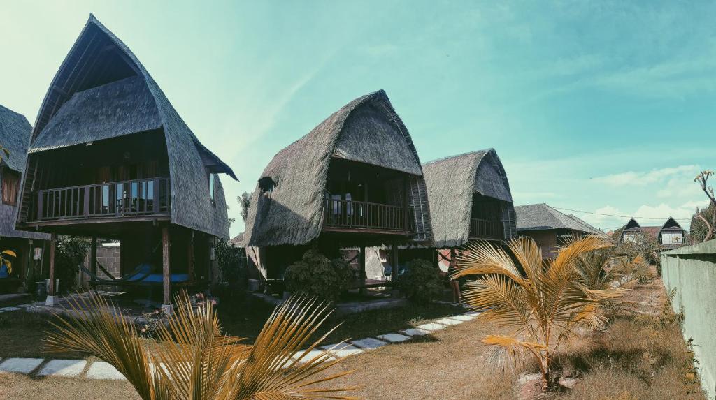 a group of houses with pointed roofs at Suka Beach Bungalow in Nusa Lembongan