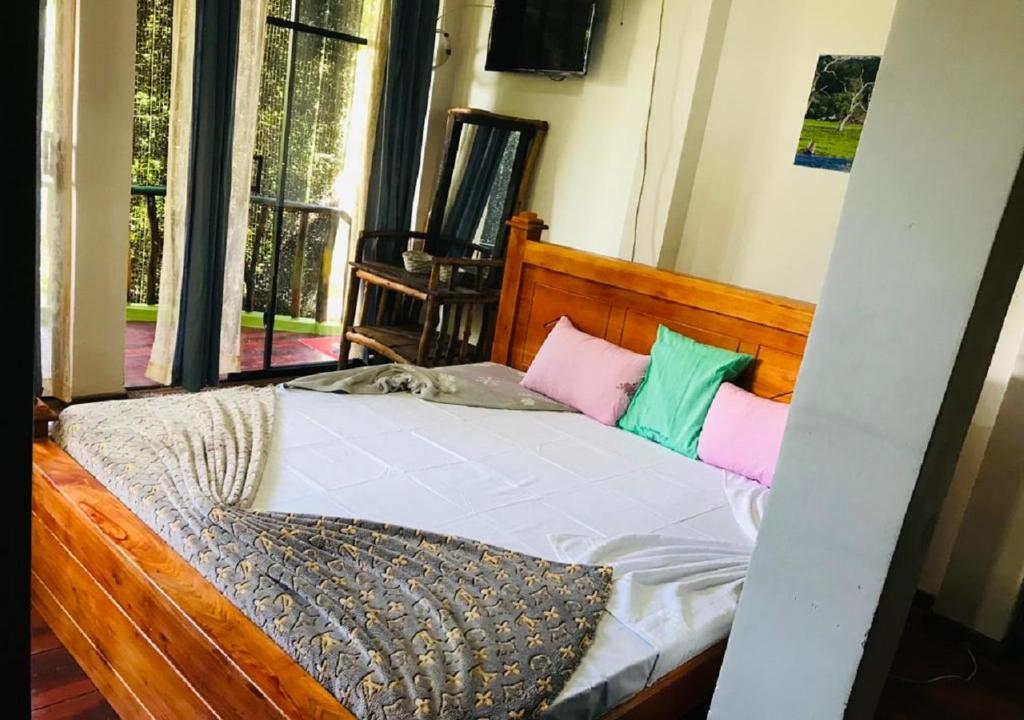エッラにあるElla Camping Resortのベッドルーム1室(木製ベッド1台、カラフルな枕付)