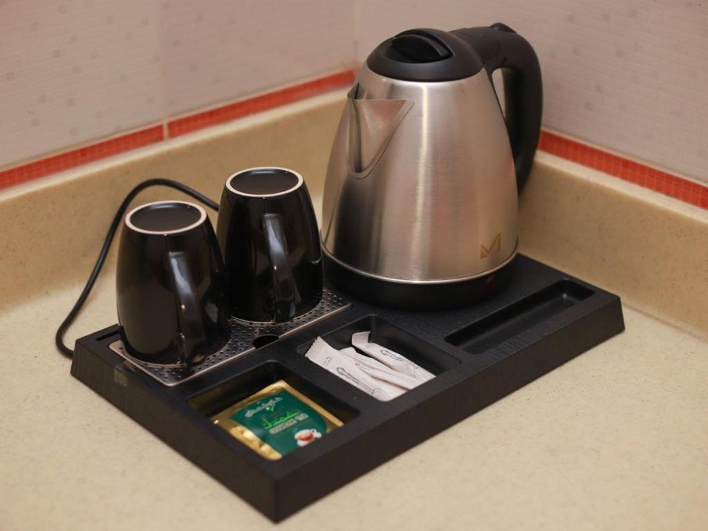 a tray with a tea kettle and cups on a counter at رواح للشقق المخدومة السداد in Taif