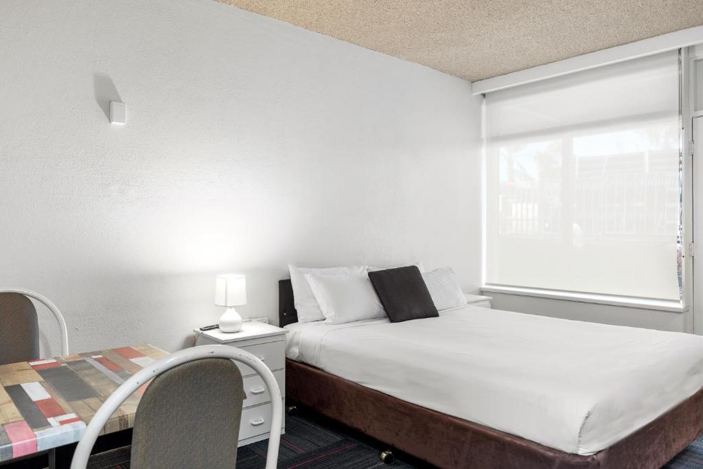 a small bedroom with a bed and a window at Red Carpet Motel in Mount Gambier