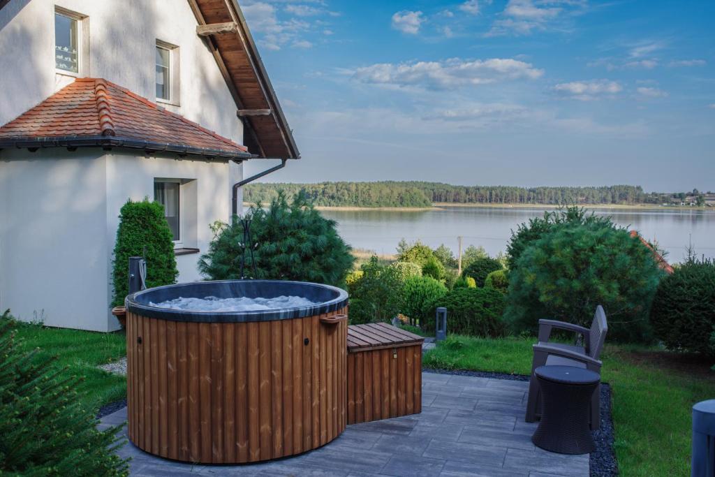LipnicaにあるDom na wzgórzu z widokiem na jezioro z balią i saunąの湖のある家の庭にある大型ホットタブを利用できます。