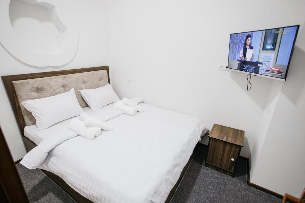 Schlafzimmer mit einem weißen Bett und einem TV an der Wand in der Unterkunft Nazarxan Hotel in Samarkand