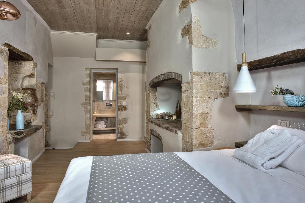 1 dormitorio con cama blanca y chimenea en Elia Zampeliou Hotel en La Canea