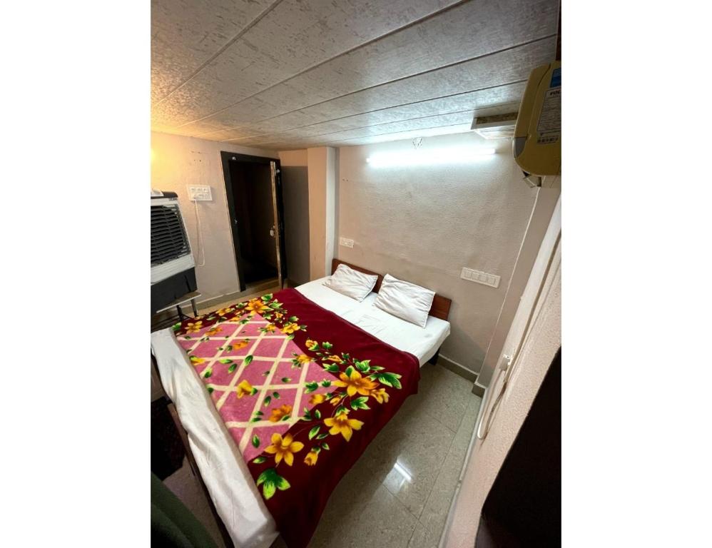 Cette petite chambre comprend un lit avec une couverture colorée. dans l'établissement Hotel Forever, Ujjain, à Ujjain