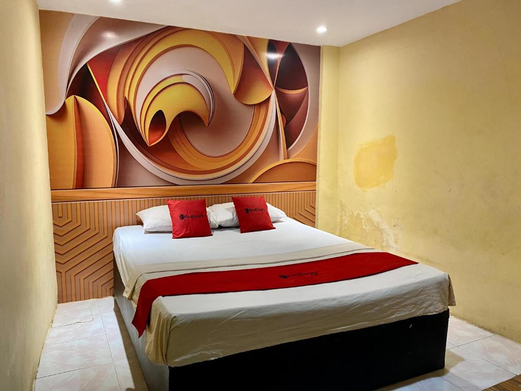 um quarto com uma cama com um quadro na parede em RedDoorz near Gedung Kesenian Palopo em Palopo