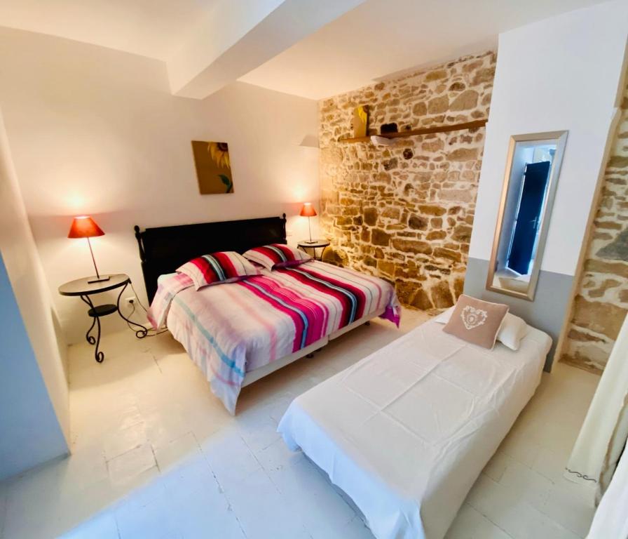 1 dormitorio con cama y pared de piedra en Les chambres de la Villa EUGÉNIE, en Lézignan-Corbières