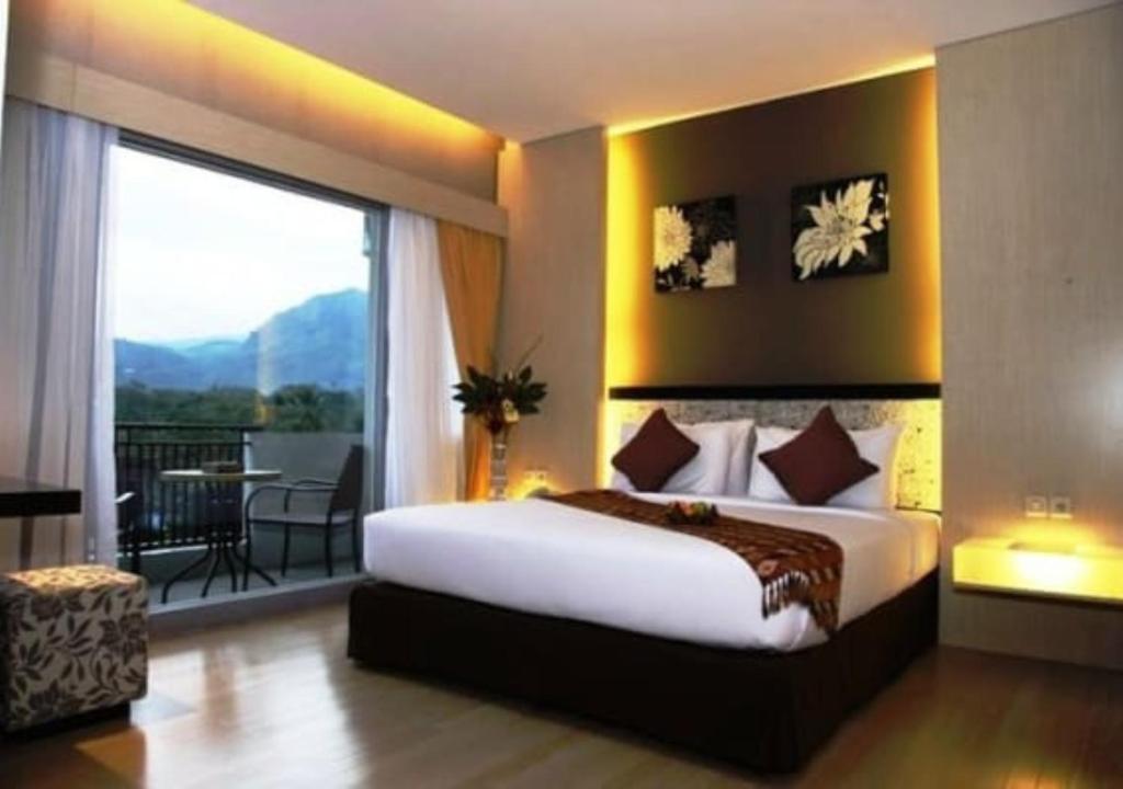 a bedroom with a large bed and a large window at Hotel Agung Putra in Banyumas