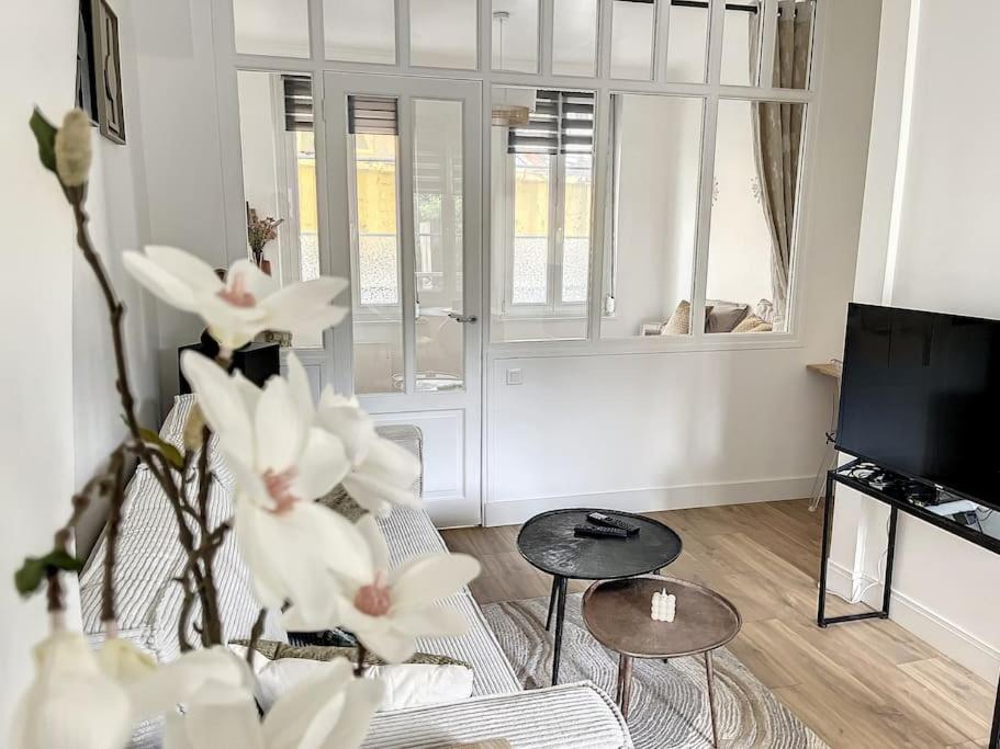 un salon avec des fleurs blanches et une télévision dans l'établissement Le Huitième - Chic et Branché, à Compiègne
