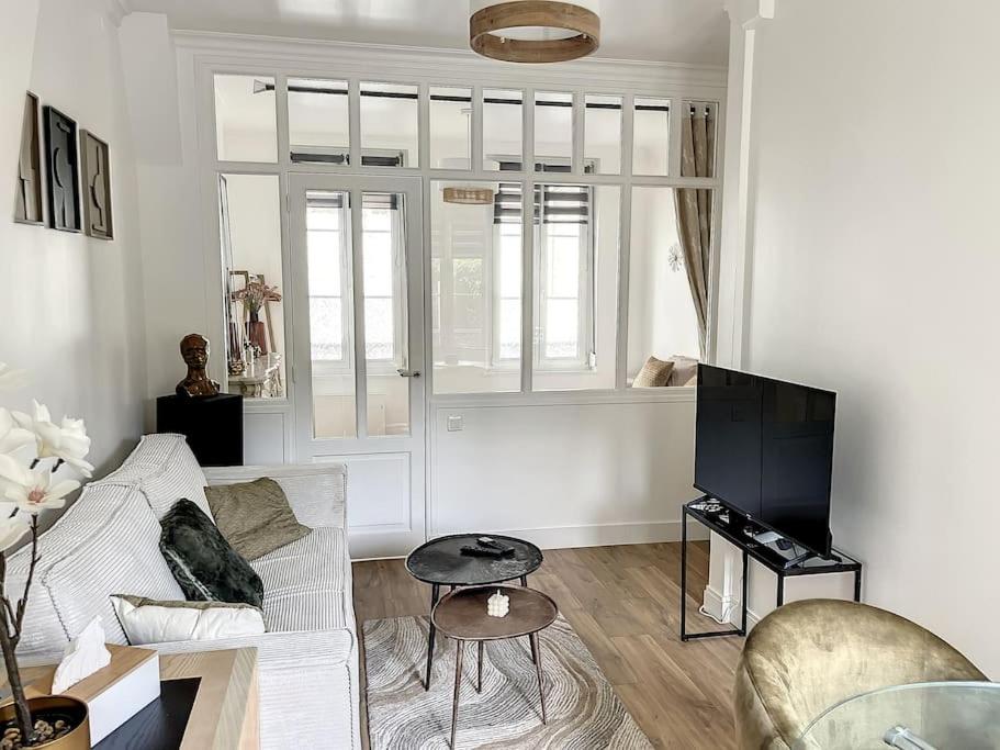 a living room with a white couch and a tv at Le Huitième - Proche centre ville in Compiègne