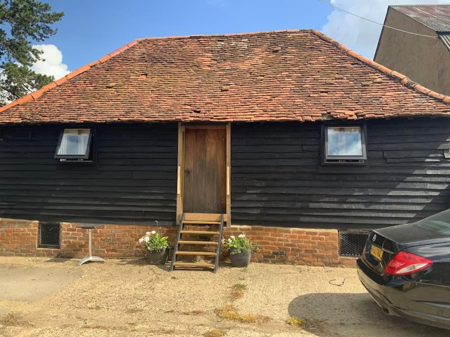 a black house with a wooden door and a ladder at The Granary at Duchess Farm in Sawbridgeworth