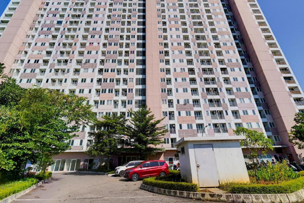 a tall building with cars parked in front of it at OYO Life 92874 Apartement Grand Sentraland Karawang By Red Dragon in Karawang