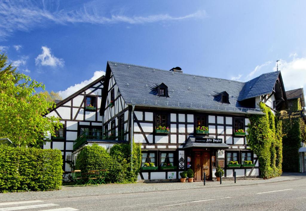 ein großes Schwarz-Weiß-Gebäude mit Büschen und Bäumen in der Unterkunft Romantik Hotel Alte Vogtei in Hamm