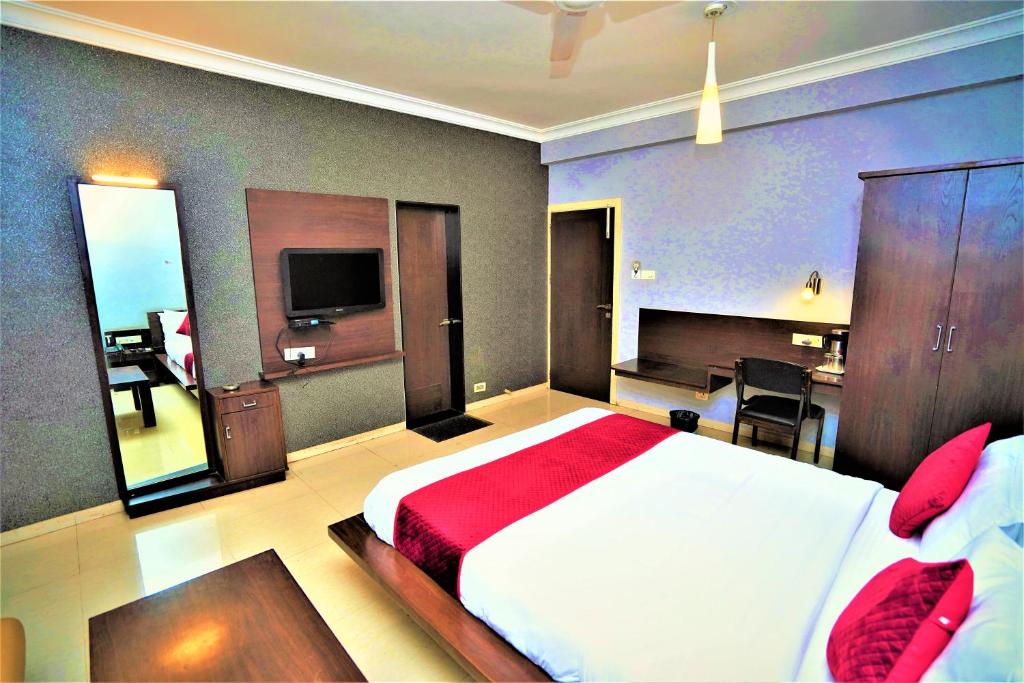 a bedroom with a large bed and a television at New Hotel Europa Inn in Rajkot