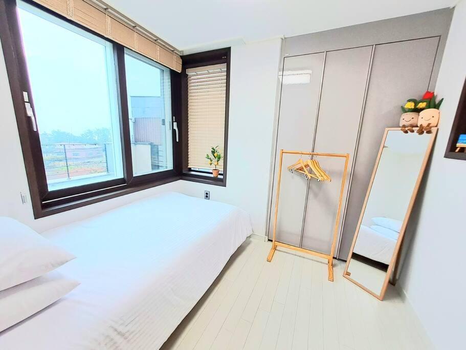 a bedroom with a bed and a window and a mirror at Siyoung's House in Jeju