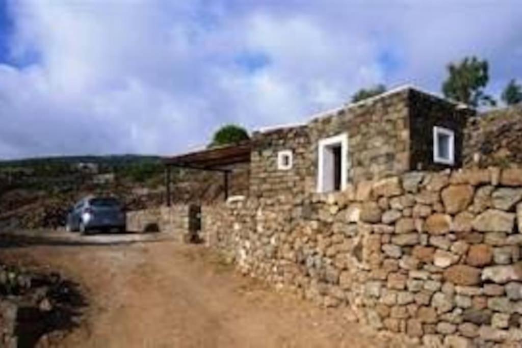 a stone building with a car parked next to it at Dammusino: mini-appartamento in Pantelleria