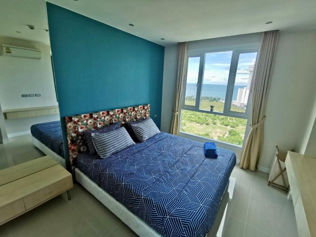 a bedroom with a bed with a blue wall and a window at Grande Caribbean Condo Resort by PTN in Pattaya South