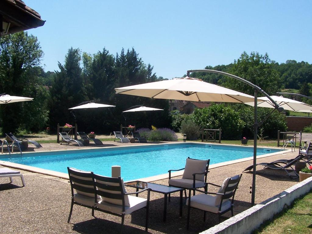- une piscine avec des chaises, des parasols, une table et des chaises dans l'établissement Domaine de Granval Chambres d'Hôtes, à Bretenoux