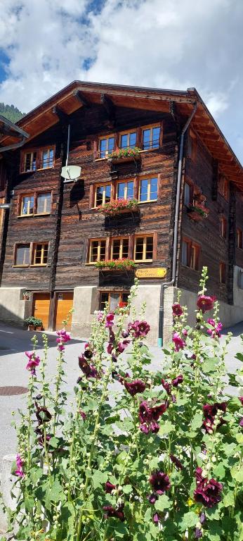un edificio de madera con flores delante en Alpensonne en Reckingen - Gluringen