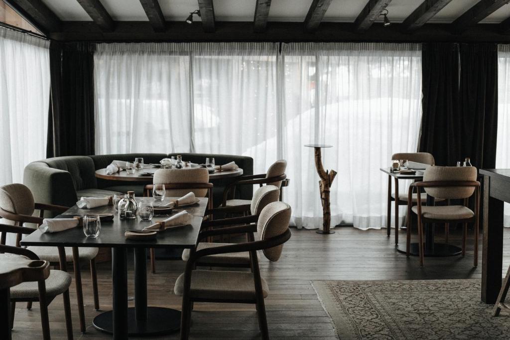 a dining room with tables and chairs and windows at L'Alpaga, a Beaumier hotel in Megève