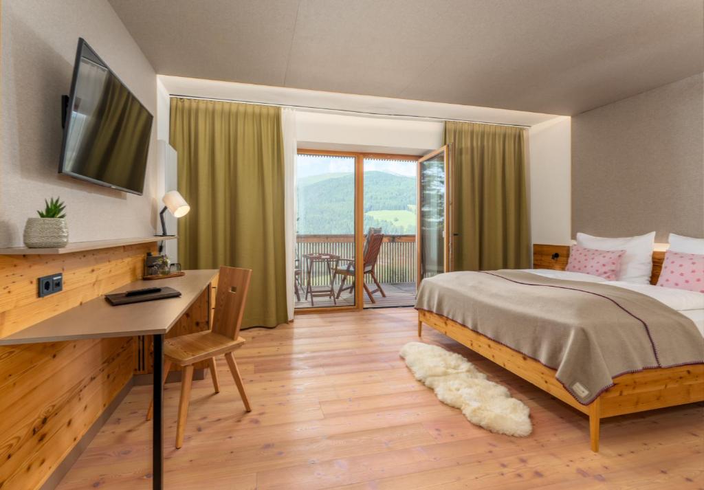 a bedroom with a bed and a desk and a balcony at Seetalblick in Sankt Wolfgang