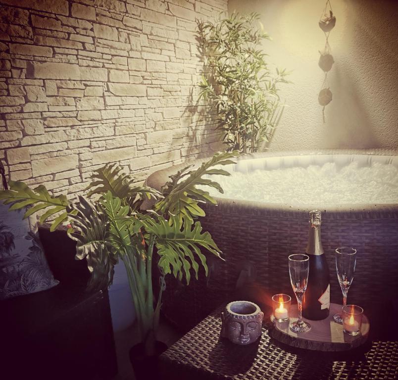 Zimmer mit einer Badewanne und einem Tisch mit Kerzen in der Unterkunft Logement cosy avec piscine et jacuzzi privatifs 4 étoiles in Saint-Dolay