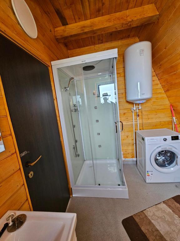 een badkamer met een douche en een wasmachine bij Cabana Corbilor The Raven's Hut in Vatra Dornei