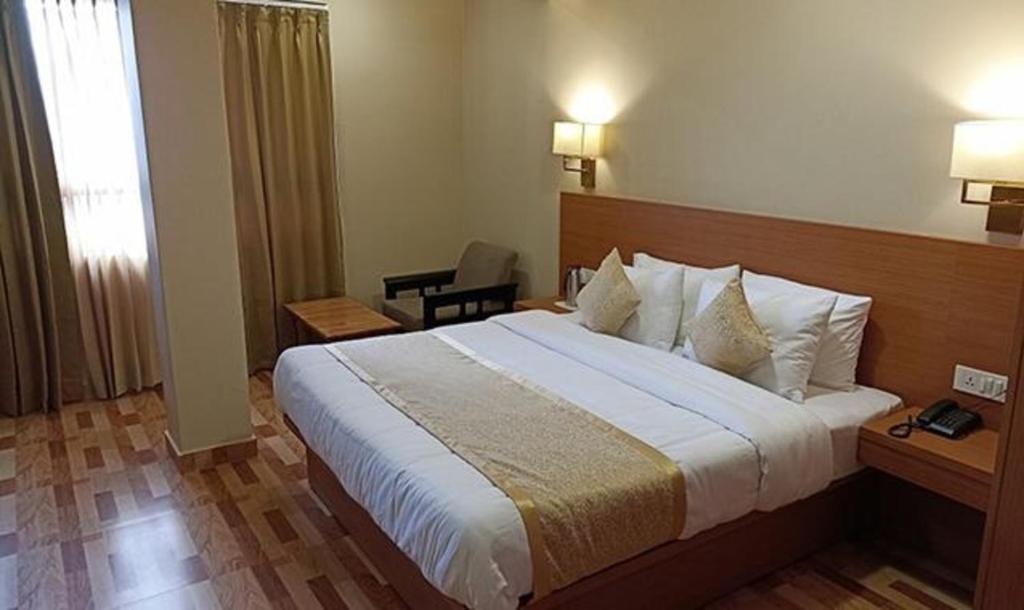 um quarto de hotel com uma cama grande e uma janela em FabHotel Prime Denzong Shiron em Gangtok