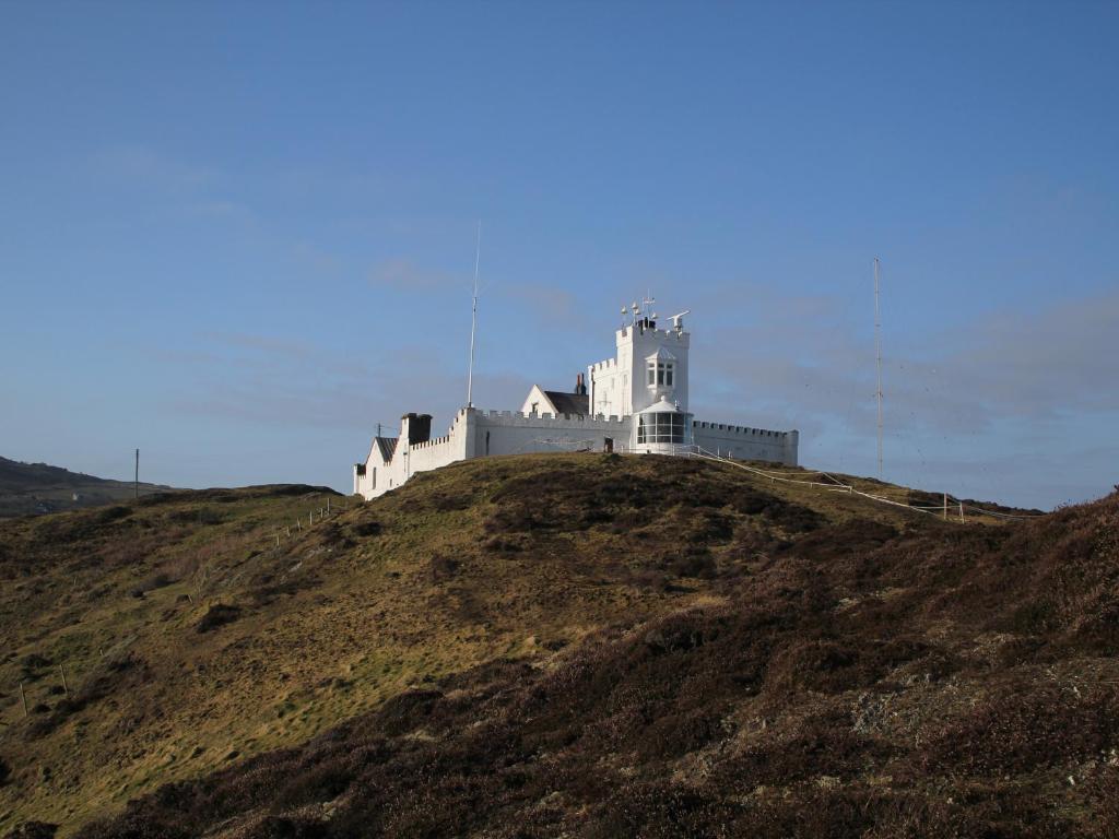 a white castle on top of a hill at West Point Lynas Lighthouse Keeper's Cottage in Amlwch