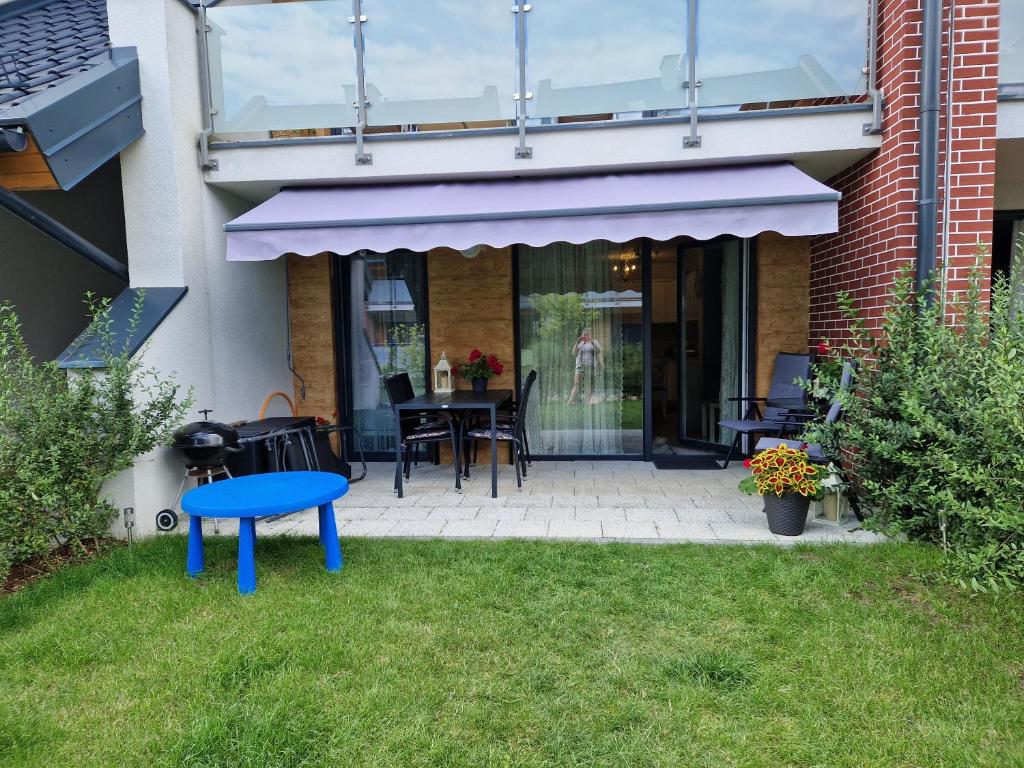 a patio with a blue table in the grass at Apartament Klaudynka in Jantar