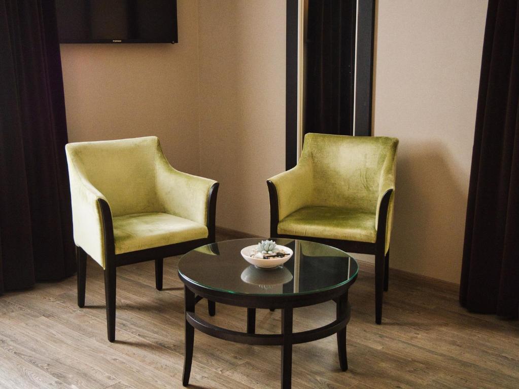 two chairs and a coffee table in a room at Amicitia - Hôtel &amp; Restaurant in LʼIsle-Adam