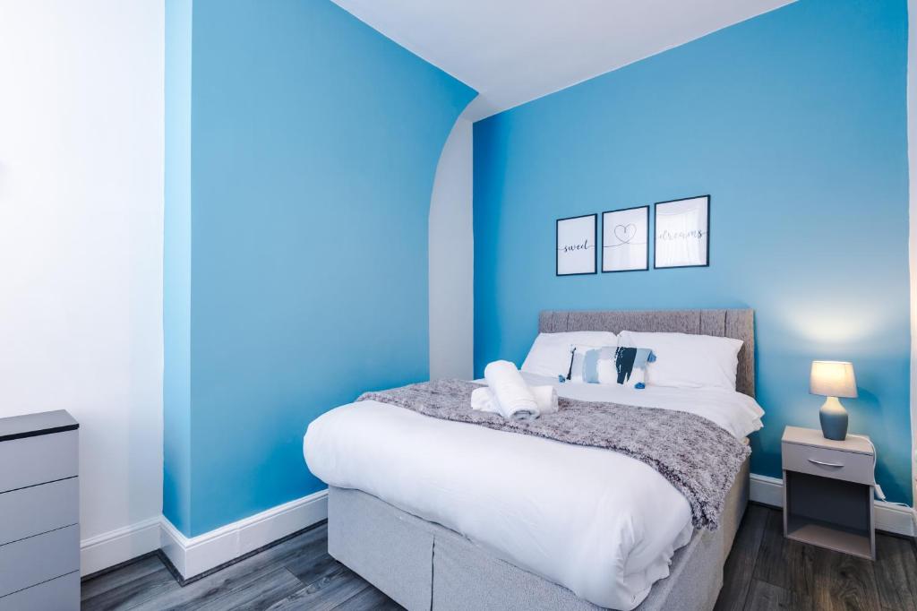 a blue bedroom with a bed and a blue wall at Spacious house near City Centre -Sleeps 8 - Parking in Liverpool