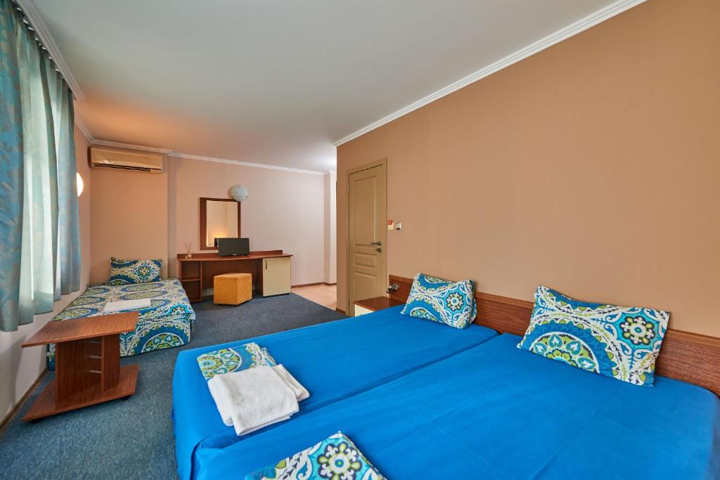 Habitación de hotel con cama azul y escritorio. en Hotel Electra, en Pomorie