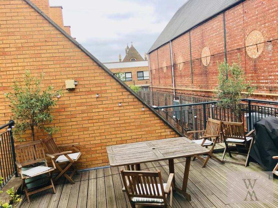 a wooden table and chairs on a balcony with a brick wall at Spacious Mews Apartment, Clapham in London