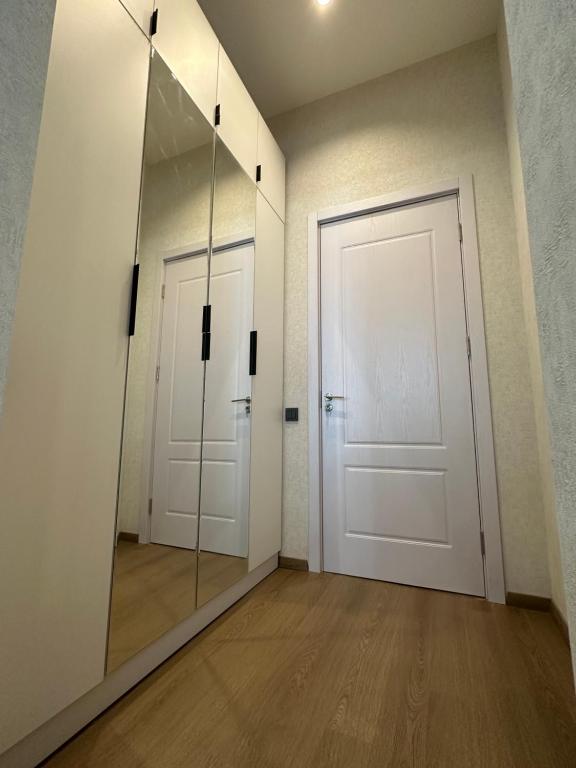 um corredor com um espelho e uma porta branca em Apartment em Tbilisi