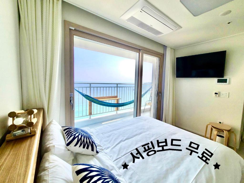 a bedroom with a bed and a large window at SurfingStay in Yangyang