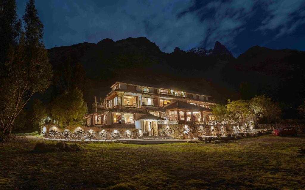 uma casa grande com luzes em frente a uma montanha em CASA RAIZ Handmade House Luxury Stay em Calca