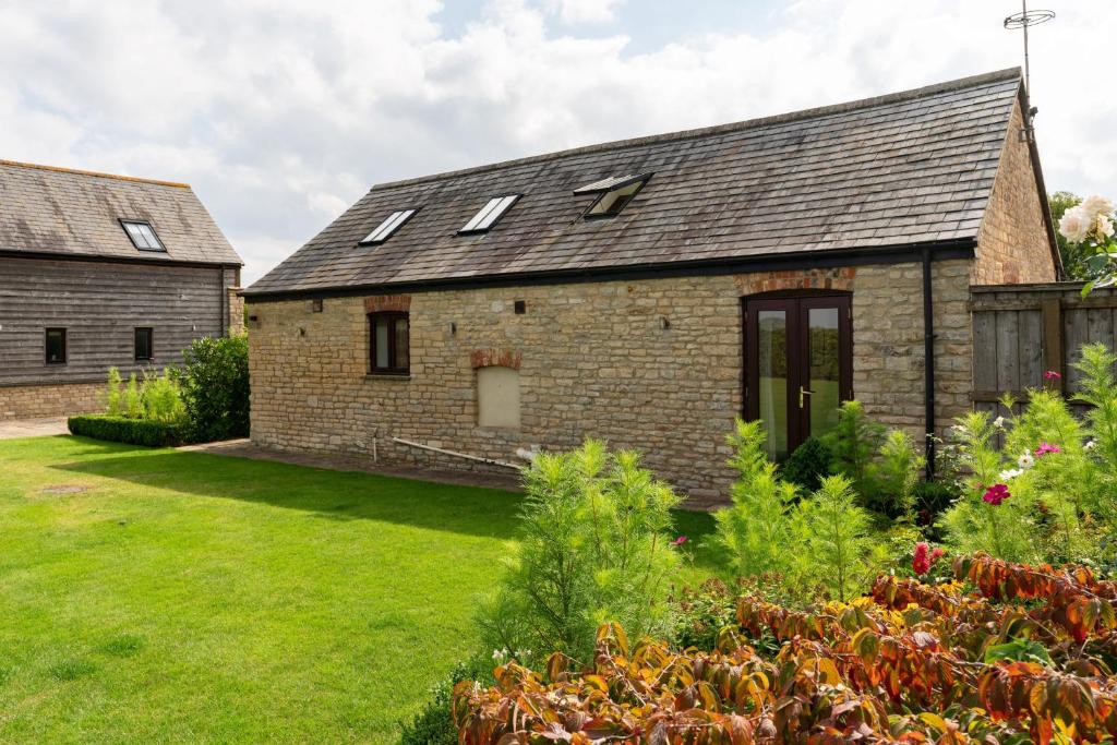 an old stone house with a garden in front of it at Coursehill Barn in Witney