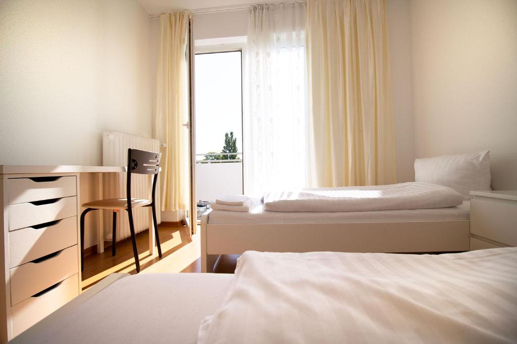 1 dormitorio con 2 camas, escritorio y ventana en Apartment Centrum Bergisch Gladbach en Bergisch Gladbach