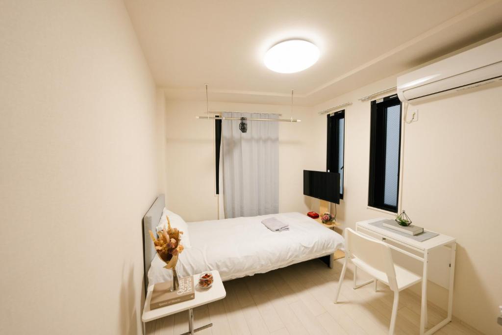 1 dormitorio con 1 cama, escritorio y TV en FL Residence Shinjuku II, en Tokio